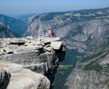 Two people standing on Half Dome's Visor with valley in background